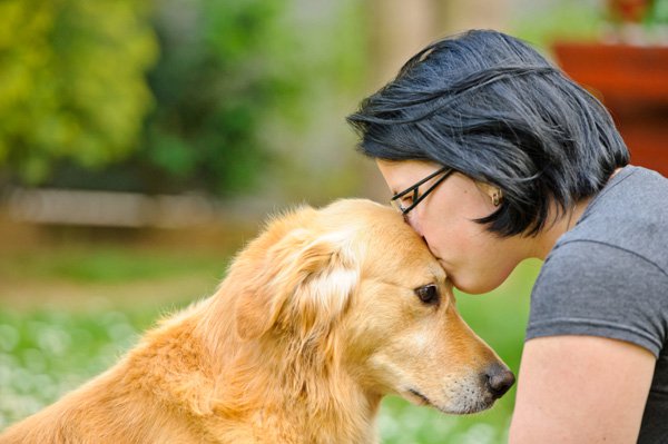 mujer besando en la frente a su mascota