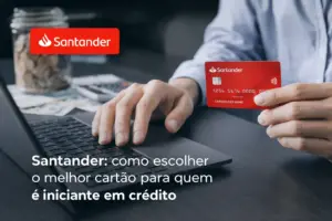 Mão segurando cartão Santander perto de laptop com jarro de moedas ao fundo